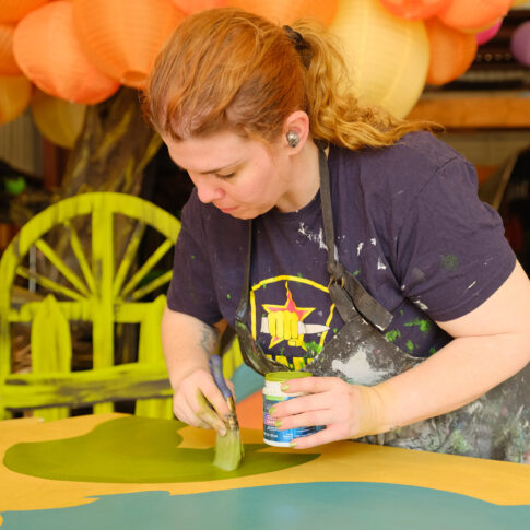 A volunteer paints details on a float.