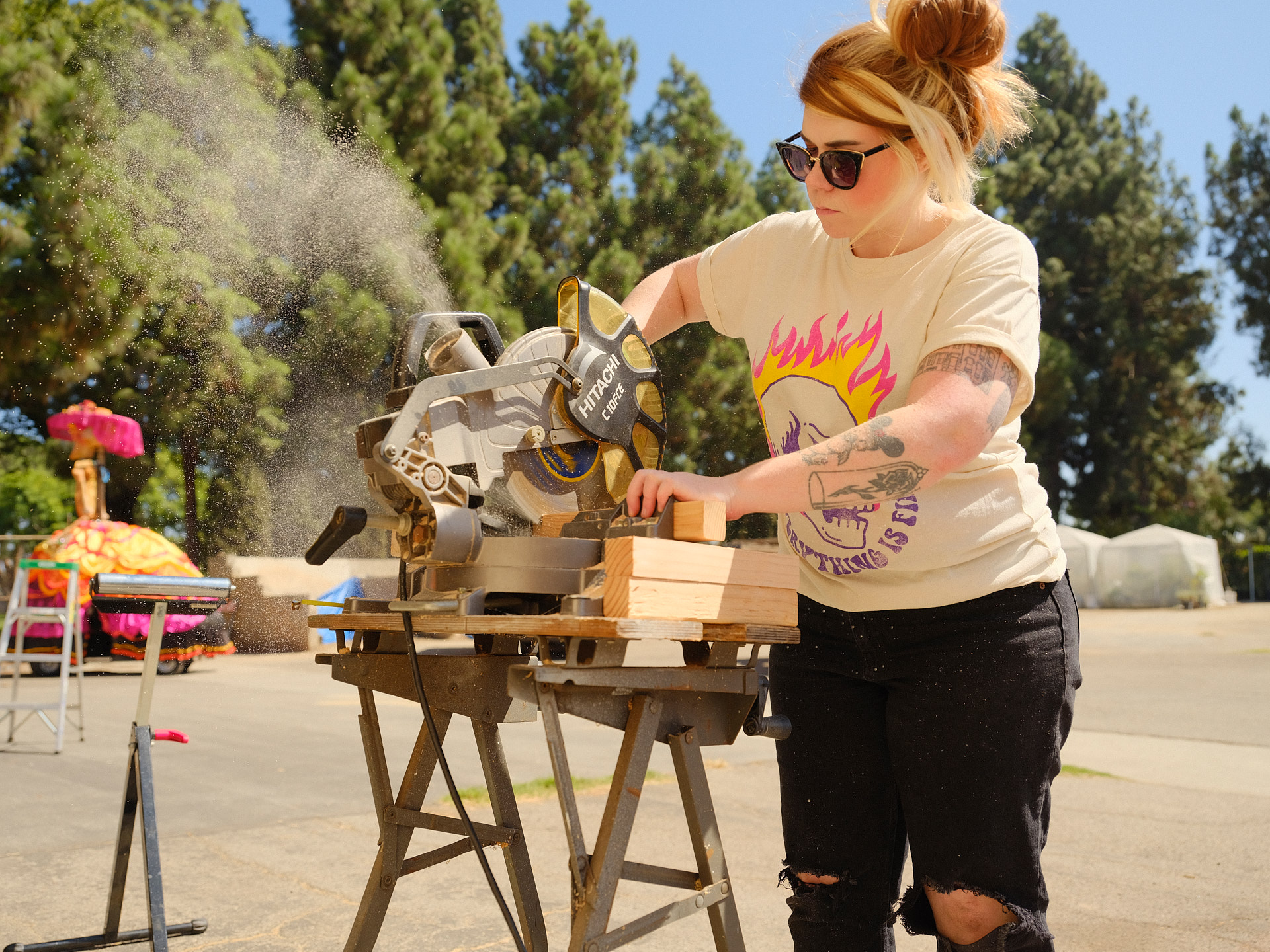 A volunteer uses a miter saw to cut wood for float construction.