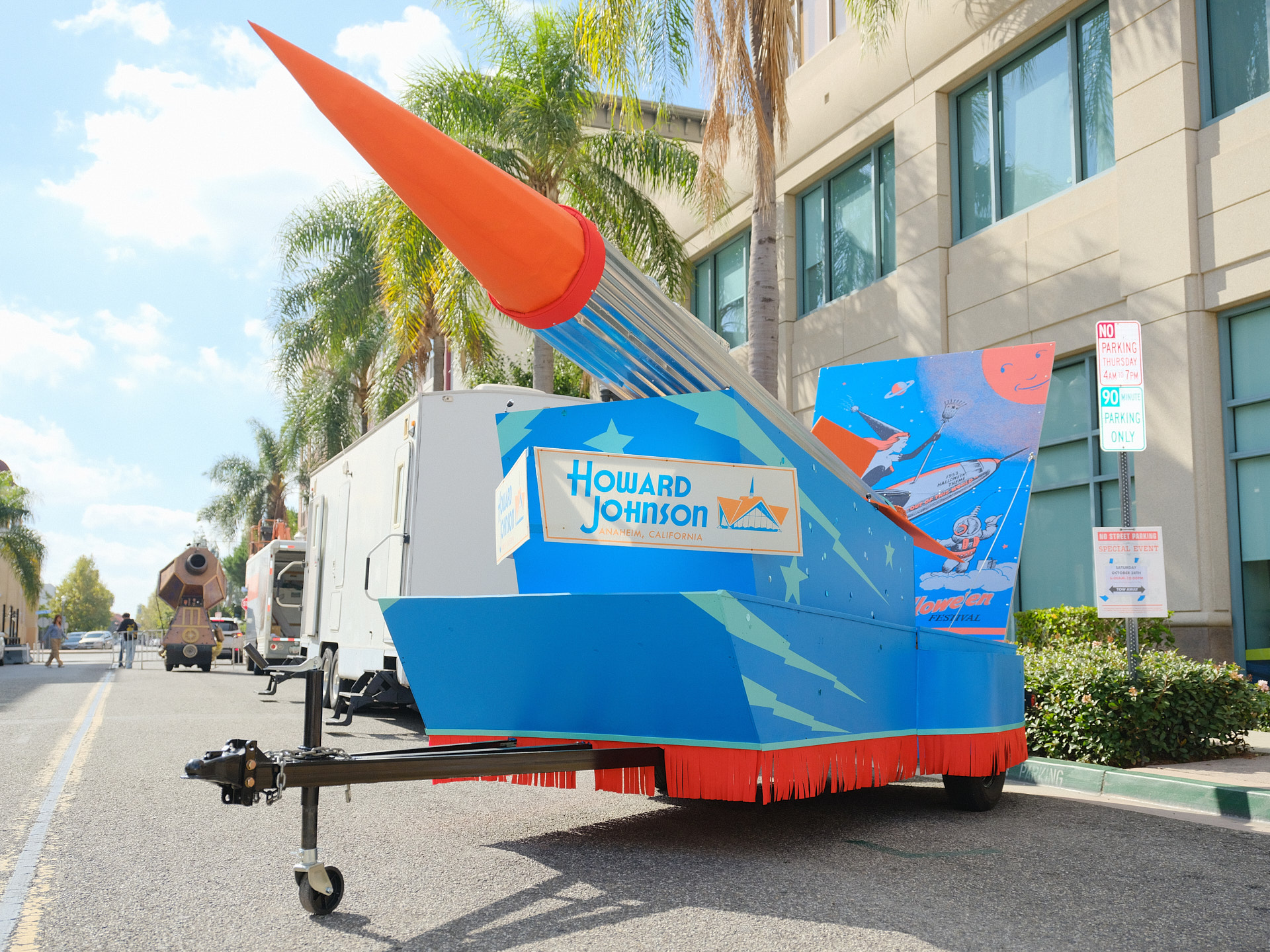 Photo of the Rocket Witch parade float. A large mid-century modern rocket sits angled on a blue base.
